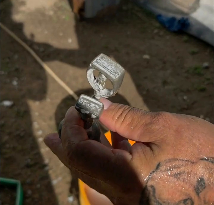 Two silver ring casts, still in the plaster, held over the quench bucket