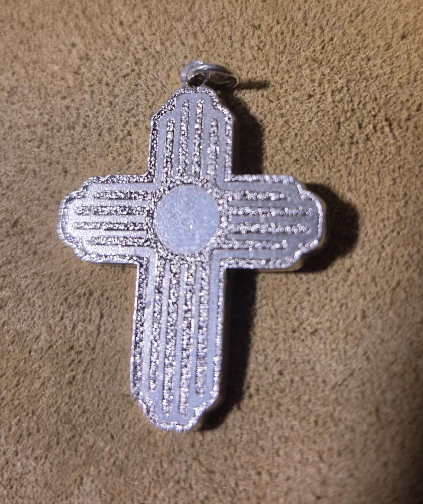 A silver Zia cross on suede